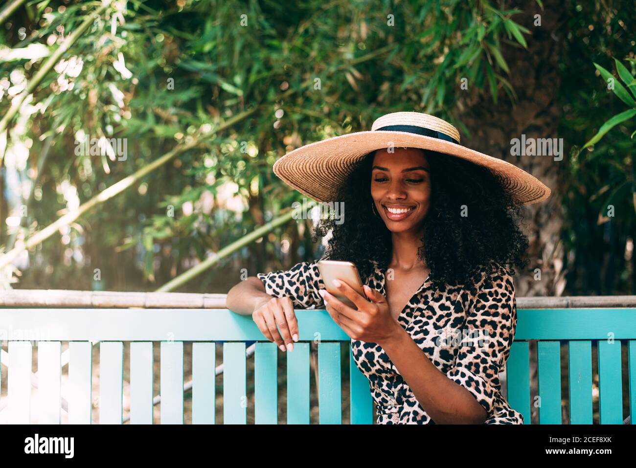 Donna seduta in un bellissimo giardino sul telefono cellulare Foto Stock
