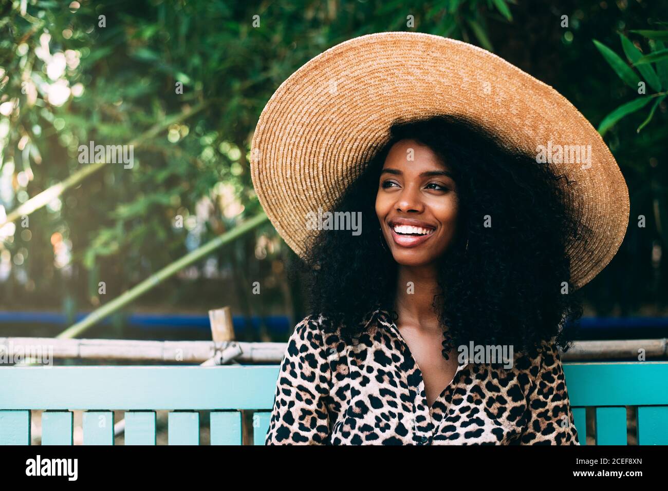 Donna con cappello di paglia seduta in un bel giardino Foto Stock