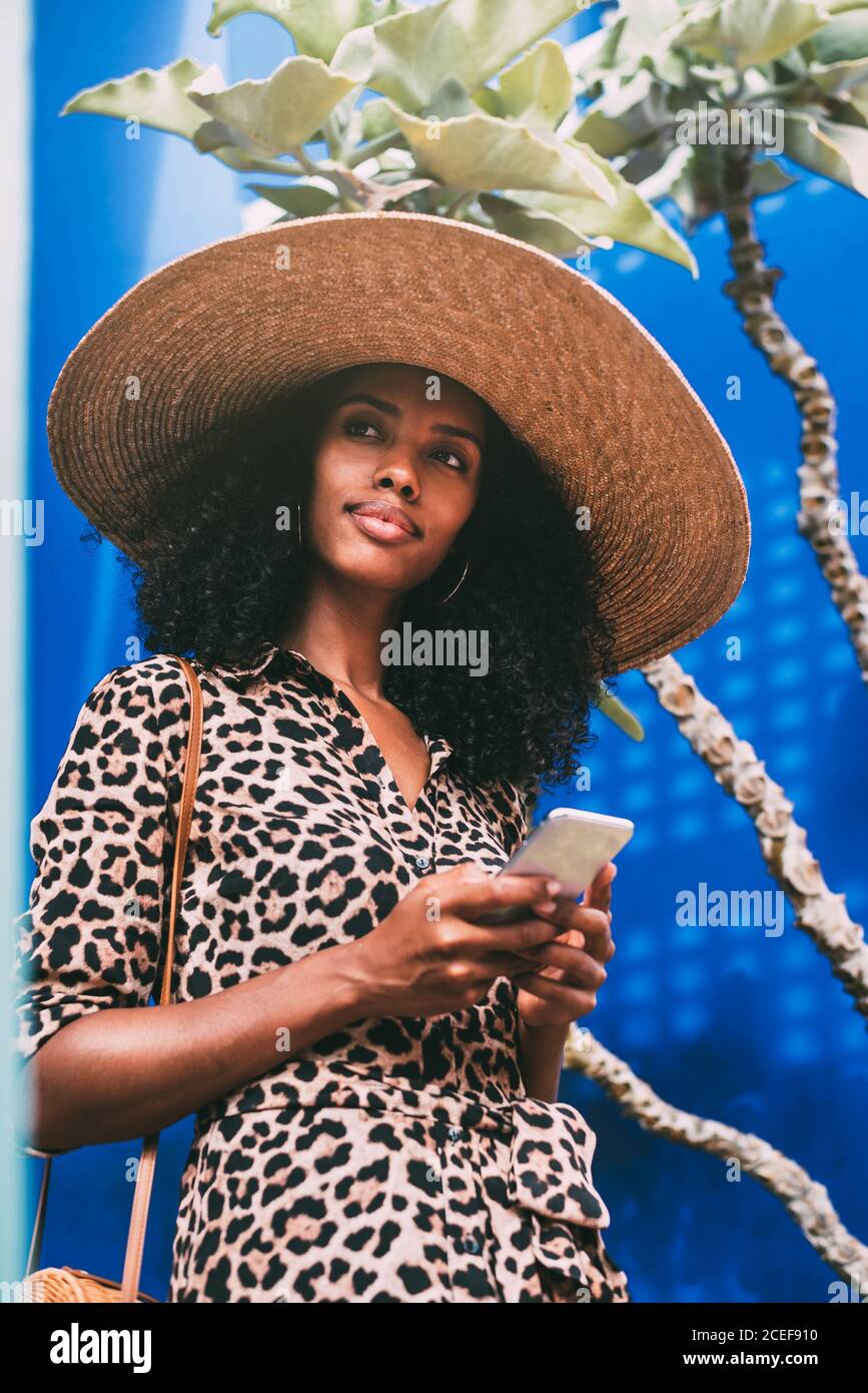 Donna con un cappello di paglia che cammina in una bella architettura parlare sul telefono cellulare Foto Stock