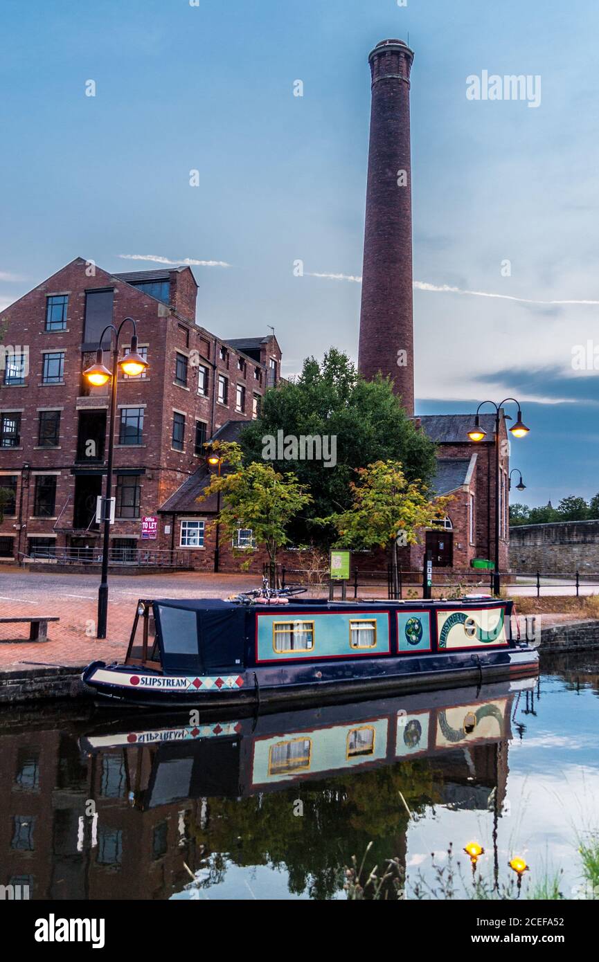 Ex mulino e camino, Salt's Wharf, Leeds & Liverpool Canal, Shipley, West Yorkshire, Inghilterra al tramonto Foto Stock