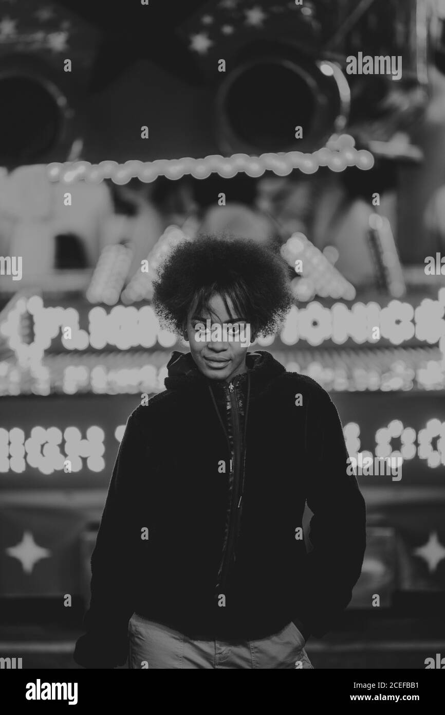 Donna nera in piedi vicino all'attrazione nel parco divertimenti Foto Stock