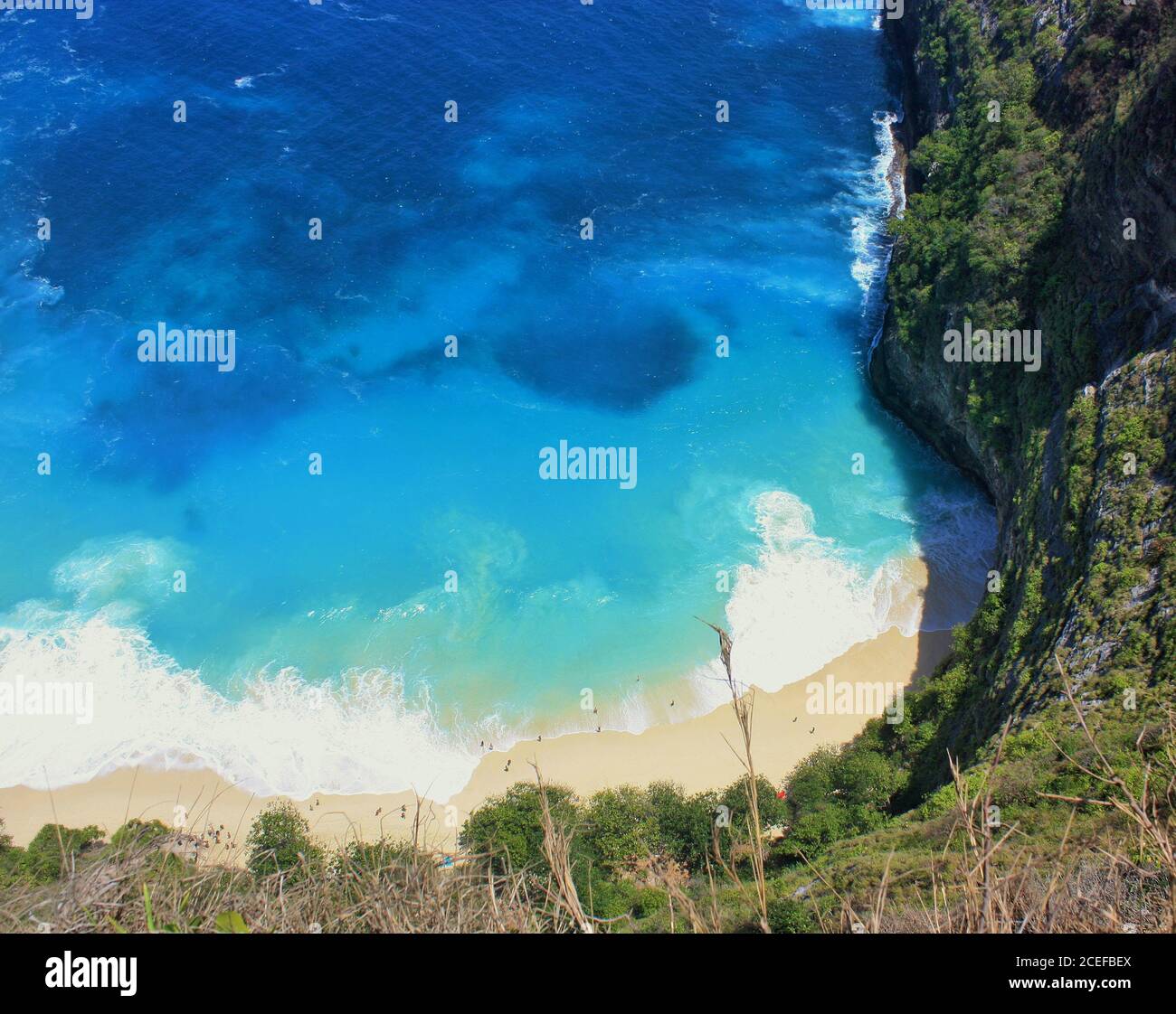 Acque blu e turchesi sotto Kelingking Beach, fondo delle scogliere T-Rex, a Nusa Penida, Indonesia Foto Stock