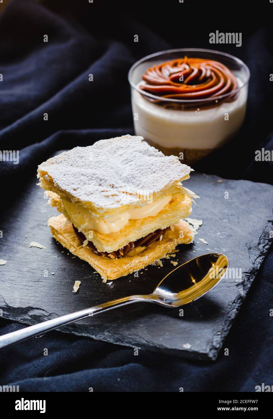 Primo piano di dessert sfoglia con creme su piatto e dessert in tazza composta da morbido tessuto. Foto Stock