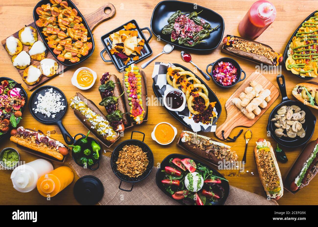 Piatto di tavolo servito con una grande quantità di snack vari e hot dog con salse e spezie, Foto Stock