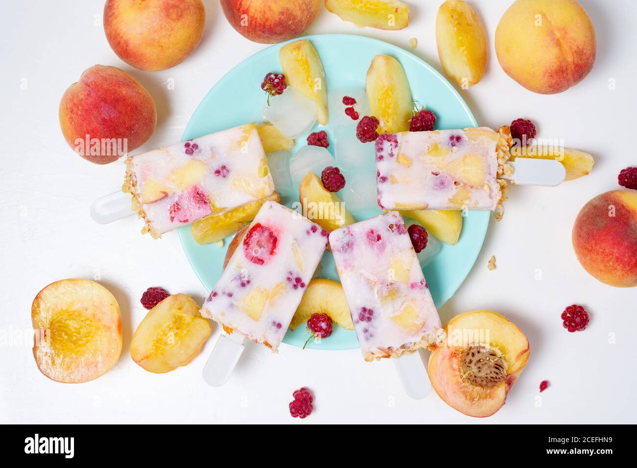 gelato estivo fresco su bastone con frutti di pesca e lamponi su sfondo chiaro. Foto Stock