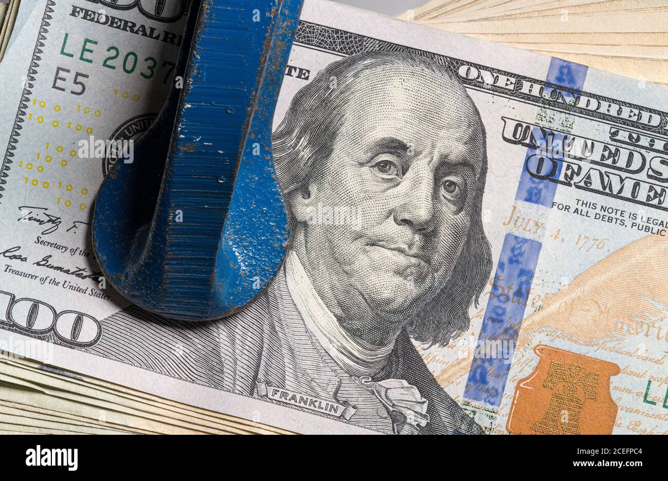 Concetto di stress finanziario o recessione. USA 100 dollari fatture essere schiacciato tra le mascelle di un grande vizio o morsa in dettaglio macro shot Foto Stock