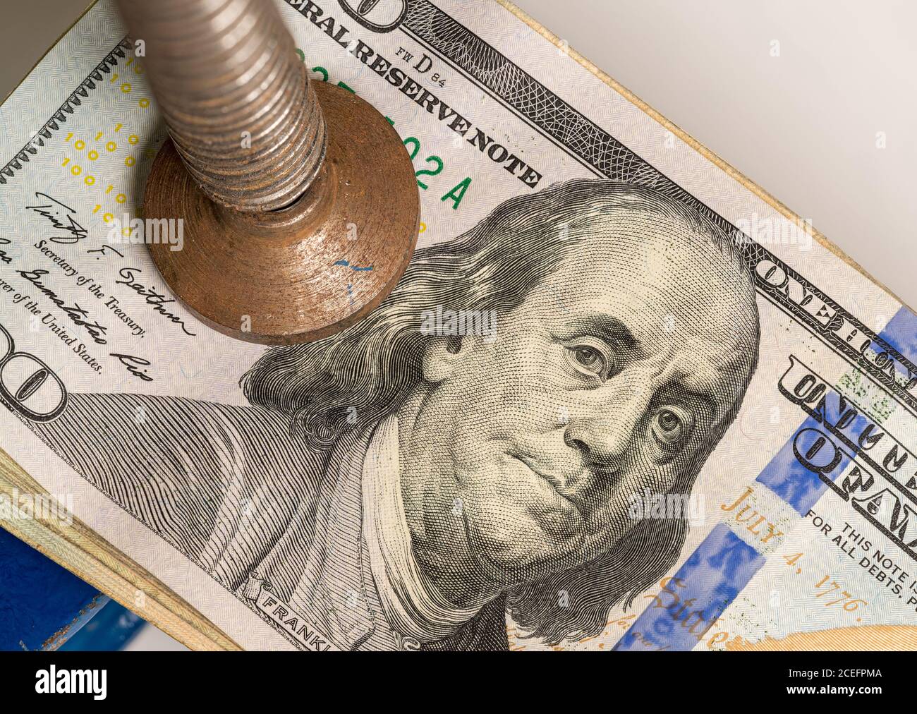 Concetto di stress finanziario o recessione. USA 100 dollari fatture essere schiacciato tra le mascelle di un grande vizio o morsa in dettaglio macro shot Foto Stock