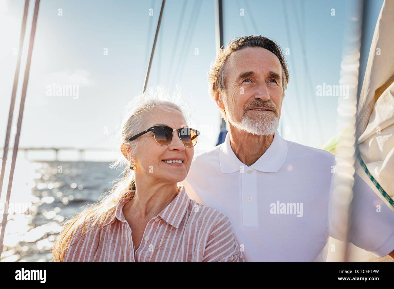 Ritratto di due anziani che guardano via. Coppia matura in piedi sullo yacht godendo il loro viaggio in barca a vela. Foto Stock
