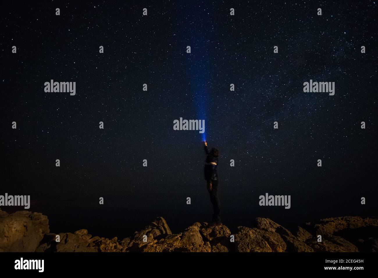 l'uomo illumina l'uomo illuminando una torcia elettrica alle stelle di notte Foto Stock