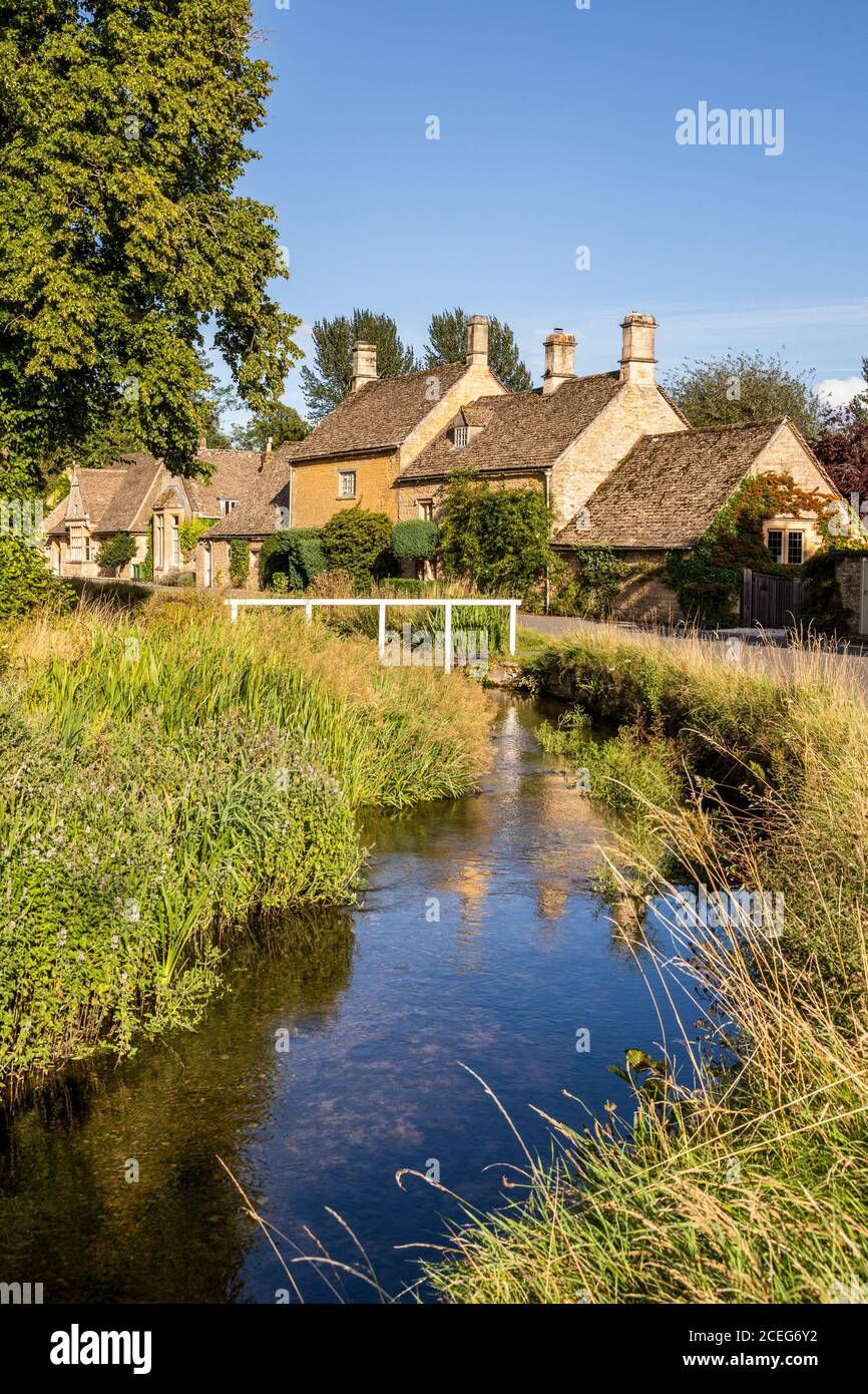 Luce serale su cottage in pietra accanto al River Eye nel villaggio di Cotswold di Lower Slaughter, Gloucestershire UK Foto Stock