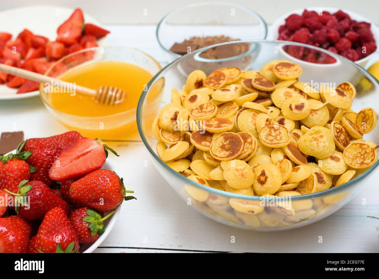 ciotola di cereali con fragole fresche cioccolato alla banana, scaglie di cocco e miele in piccoli piatti. vista dall'alto. la tendenza di se Foto Stock