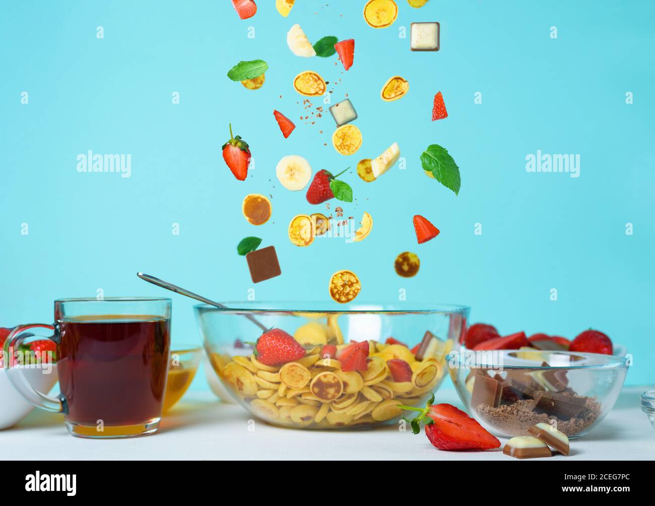 minitola per cereali con fragole fresche, banana, cioccolato, menta di cocco. tendenza all'autoisolamento. levitazione di minuscoli pancake Foto Stock