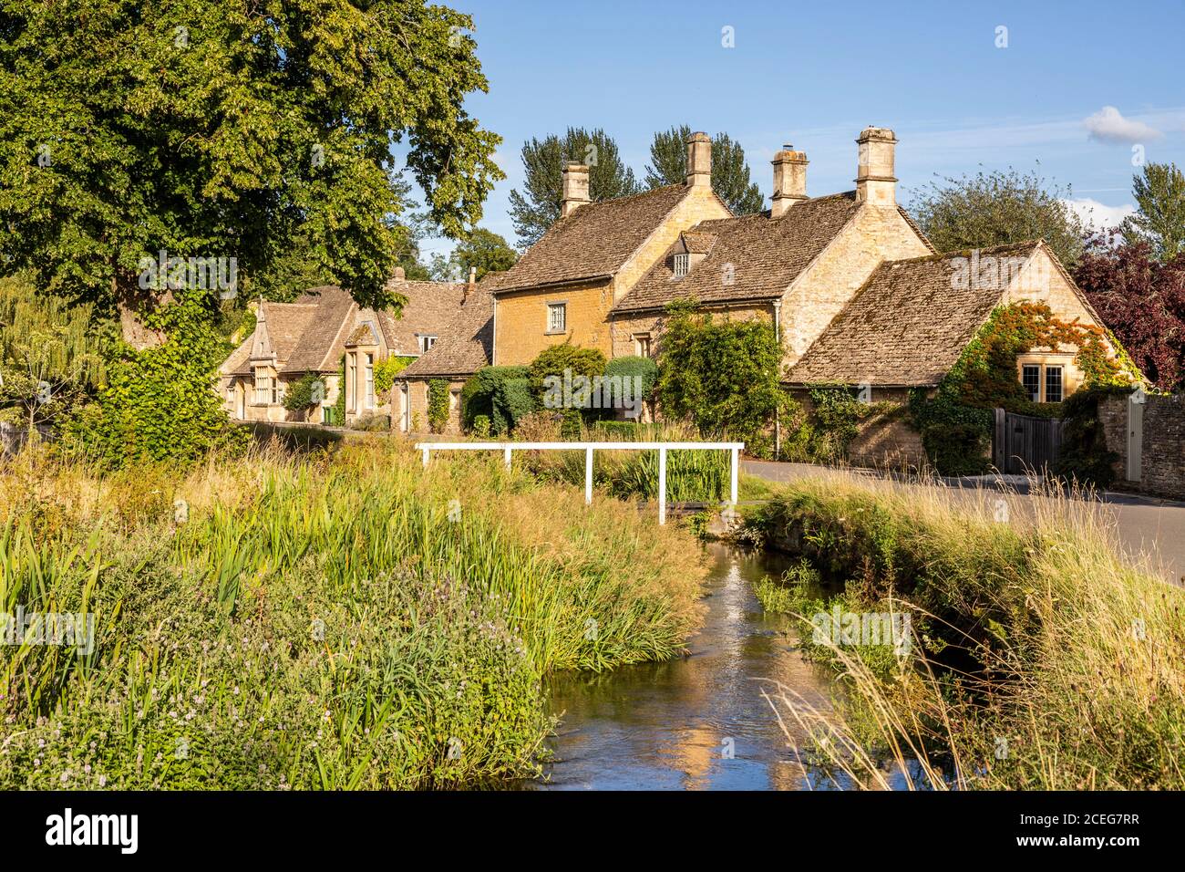 Luce serale su cottage in pietra accanto al River Eye nel villaggio di Cotswold di Lower Slaughter, Gloucestershire UK Foto Stock