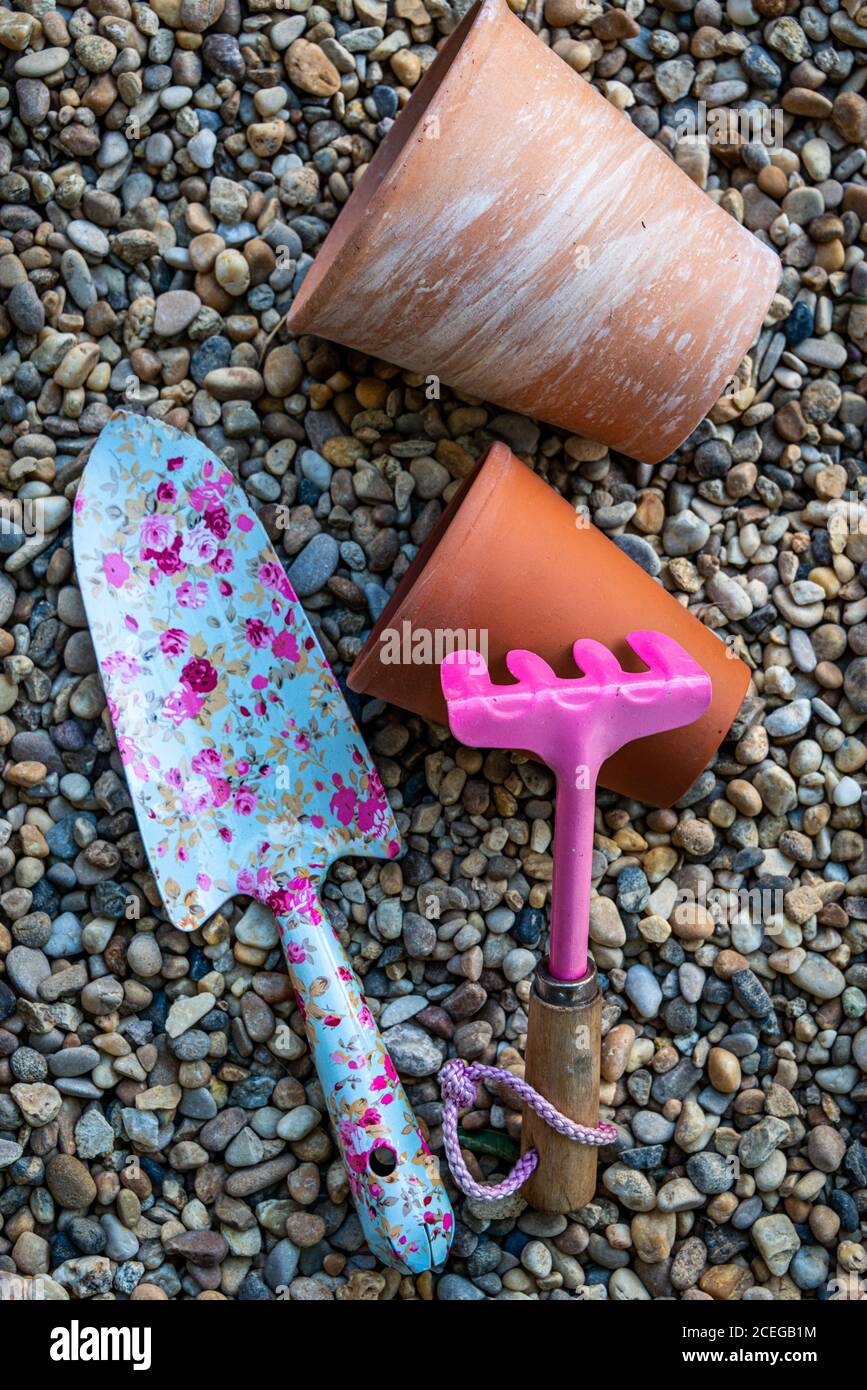 colorati utensili da giardino con vasi di fiori in terracotta su un sfondo ghiaia Foto Stock