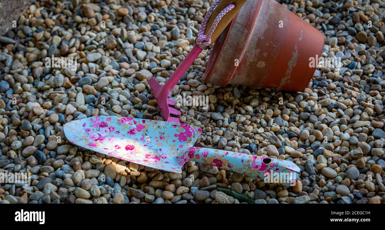 colorati utensili da giardino con vasi di fiori in terracotta su un sfondo ghiaia Foto Stock