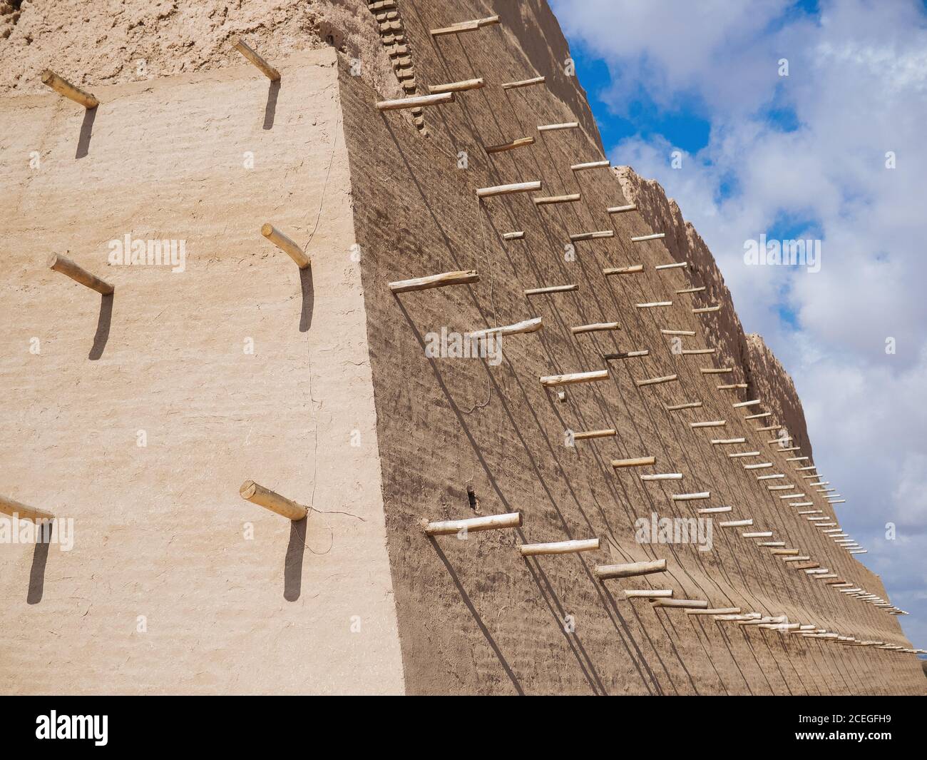 Da sotto colpo di solido enorme muro di mattoni di fortezza con balchi di legno, Uzbekistan Foto Stock