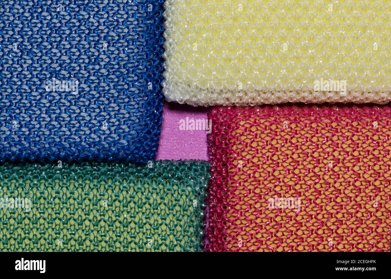 Spugne colorate per la pulizia posizionate negli angoli, immagine macro full frame. Concentrarsi sulle forme geometriche. Foto Stock