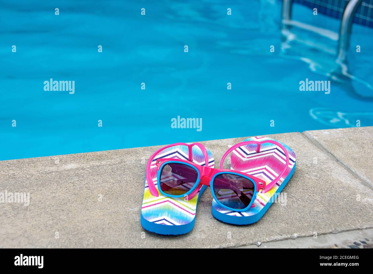 modello chevron su infradito a bordo piscina con occhiali da sole Foto Stock