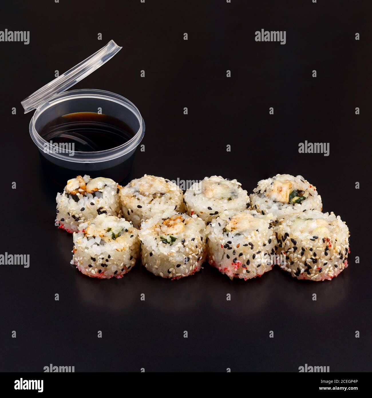 Griglia in chikken al forno a rotoli di yaki su sfondo nero con riflessi. Involtino di sushi con riso, nori, filetto di pollo, salsa di pancetta, cetriolo, parmigiano Foto Stock