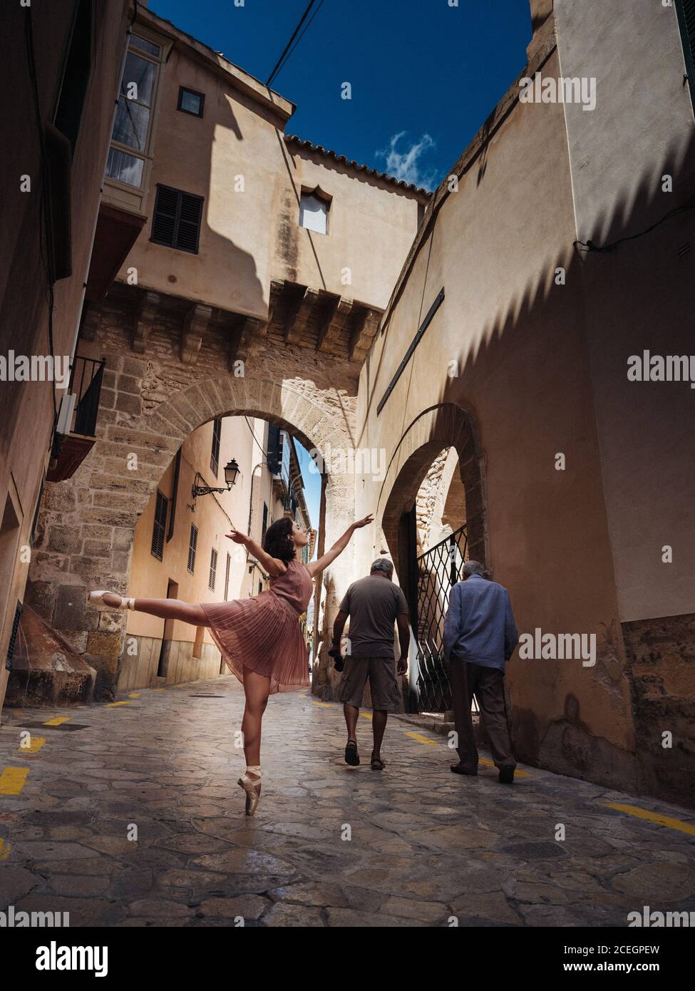 Vista laterale della bella ballerina femminile in piedi e in posa su strada soleggiata. Foto Stock