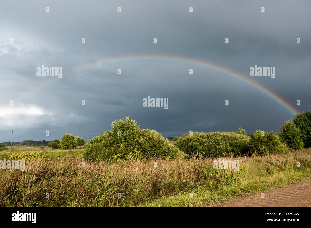 Orizzontale. In base alle condizioni meteorologiche. Arcobaleno colorato nel cielo drammatico dopo la pioggia. Foto Stock