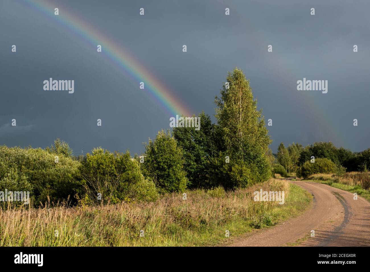 Orizzontale. In base alle condizioni meteorologiche. Doppio arcobaleno colorato nel cielo drammatico dopo la pioggia. Foto Stock