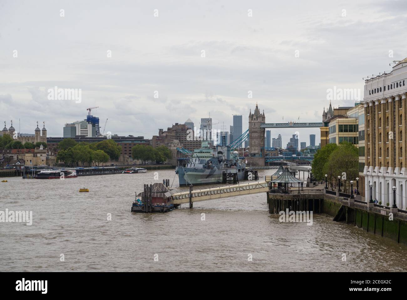 Fiume Tamigi da London Bridge verso Tower Bridge. HMS Belfast e City Pier in primo piano. Torre di Londra e Canary Wharf sullo sfondo. Foto Stock