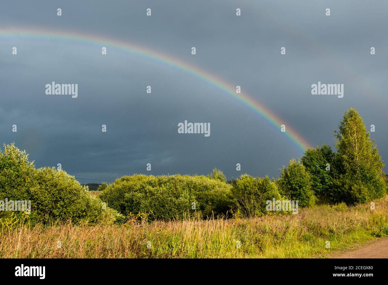 Orizzontale. In base alle condizioni meteorologiche. Doppio arcobaleno colorato nel cielo drammatico dopo la pioggia. Foto Stock