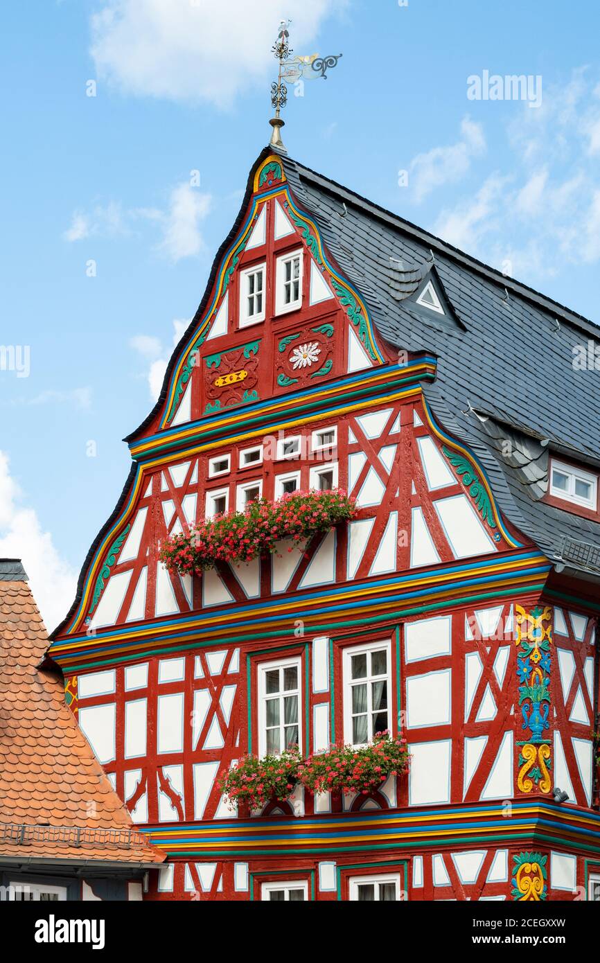 Casa tradizionale a graticcio dipinta di rosso con gerani rossi in finestre a Idstein, Assia, Germania Foto Stock