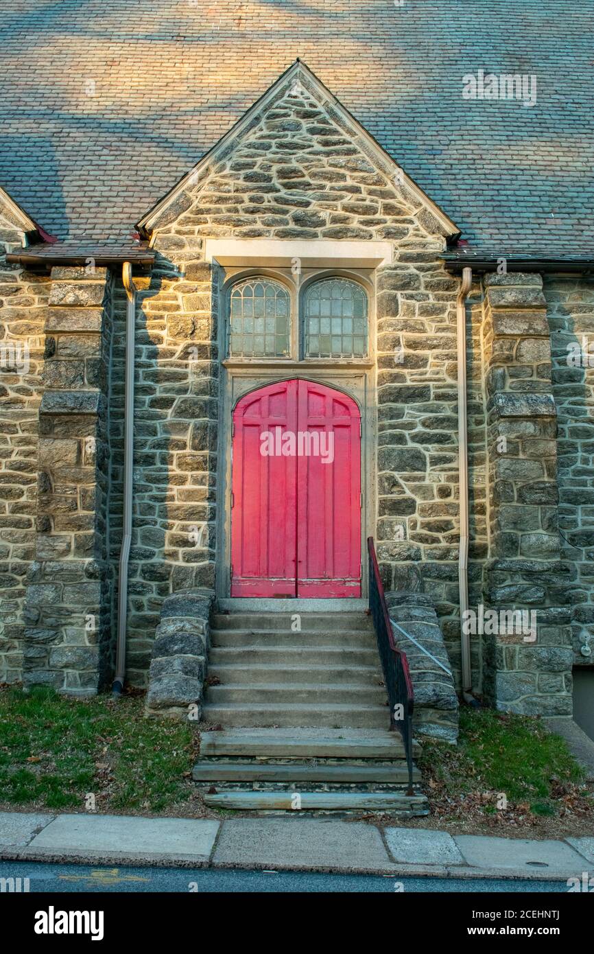 Una porta rossa luminosa in un muro di Cobblestone con Passi che conducono ad esso Foto Stock