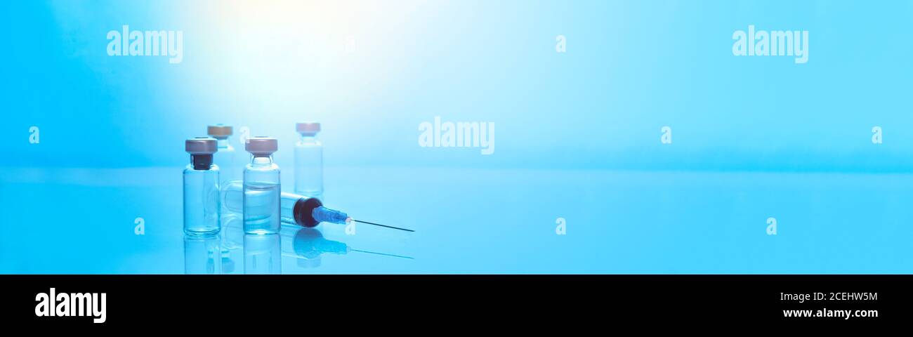 Farmaci iniettabili in fiale sigillate e una siringa medica di plastica monouso. Filtro di colore blu Foto Stock
