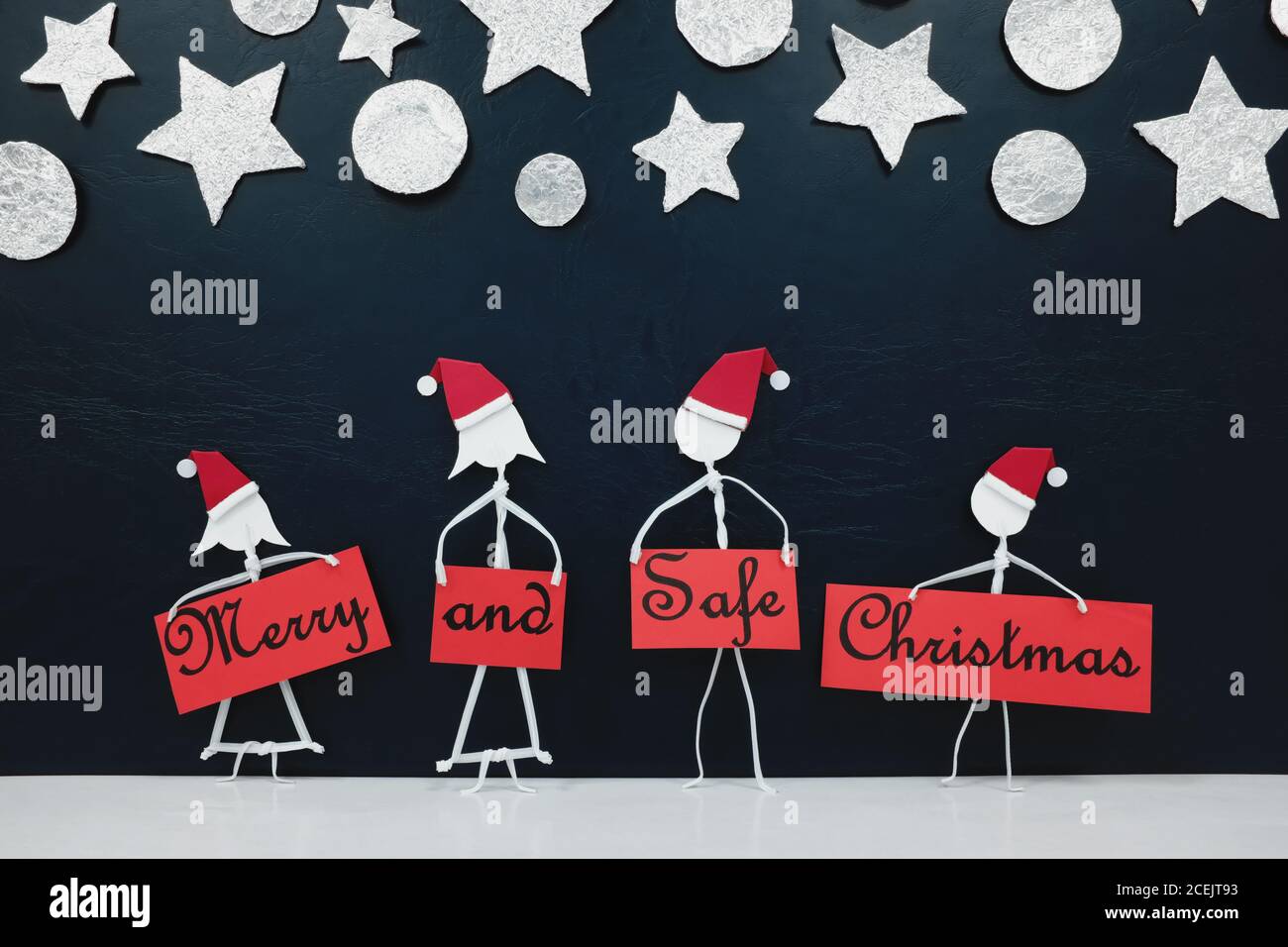 Bastone uomo famiglia figura indossare cappello di santa tenendo un rosso allegro e sicuro banner di saluto di Natale. Covid festeggiamenti concetto. Foto Stock