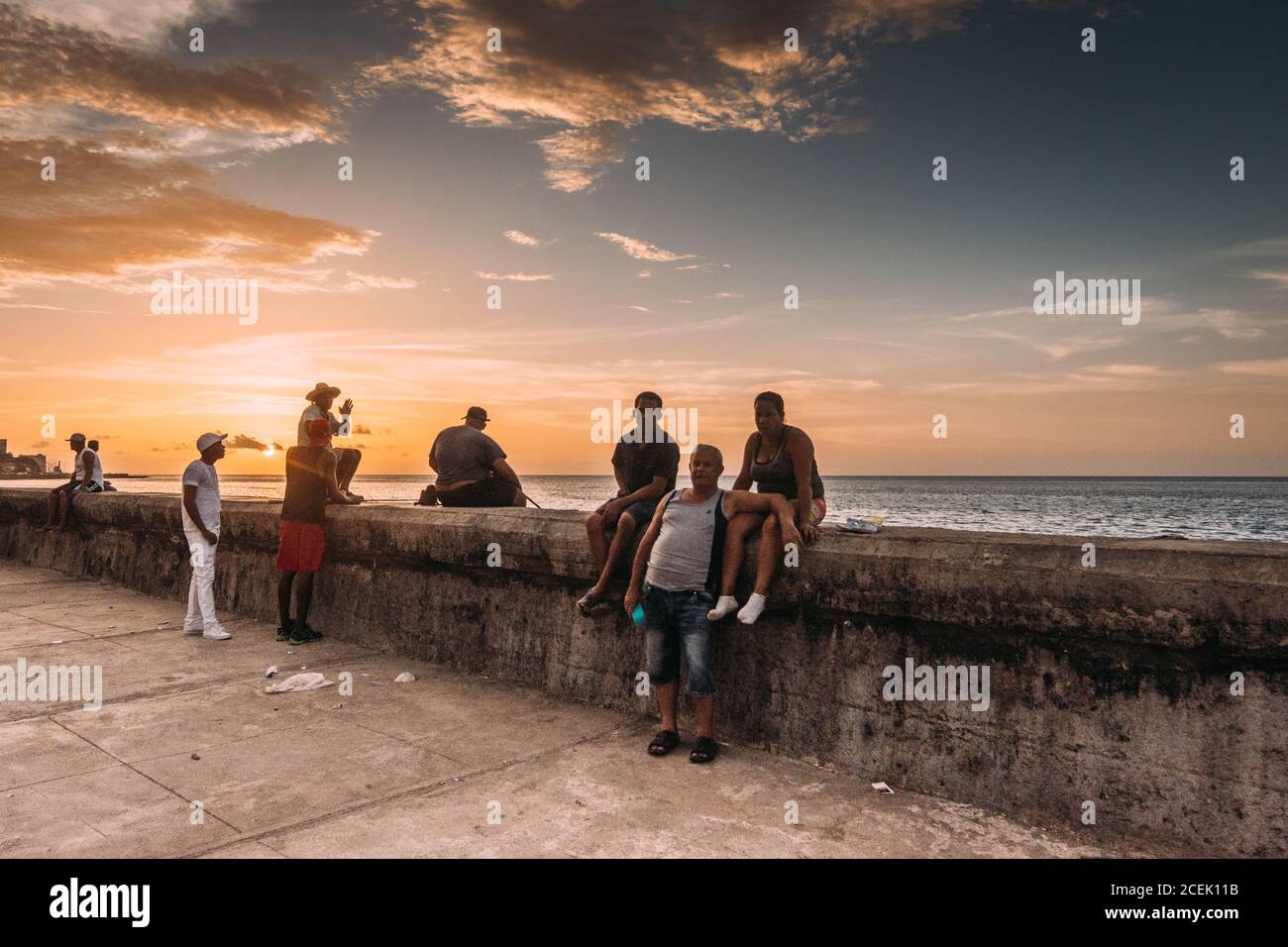 LA HABANA, CUBA - 1 MAGGIO 2018: Cittadini cubani che si agghiacciano sul lungomare pedonale di cemento sullo sfondo del cielo del tramonto, Foto Stock