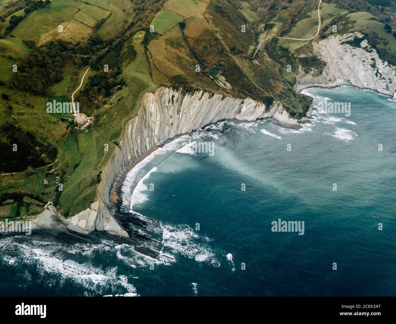 Ondulazione del mare nei pressi di colline verdi Foto Stock