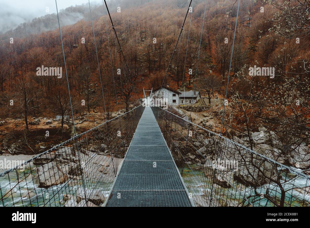 Piccolo ponte che conduce alle case del villaggio in collina in autunno. Foto Stock