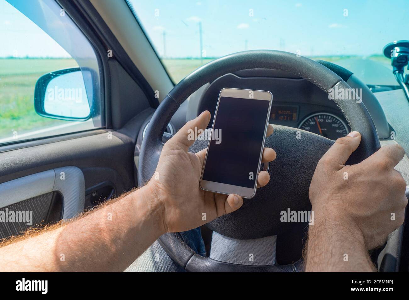 Uomo che usa il cellulare durante la guida. Utilizzo del navigatore sullo smartphone durante gli spostamenti. Foto Stock