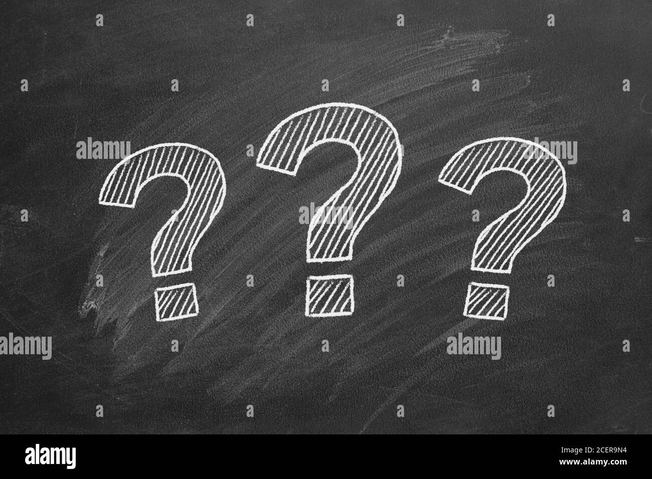 Tre punti interrogativi tracciati in gesso su una lavagna. Foto Stock