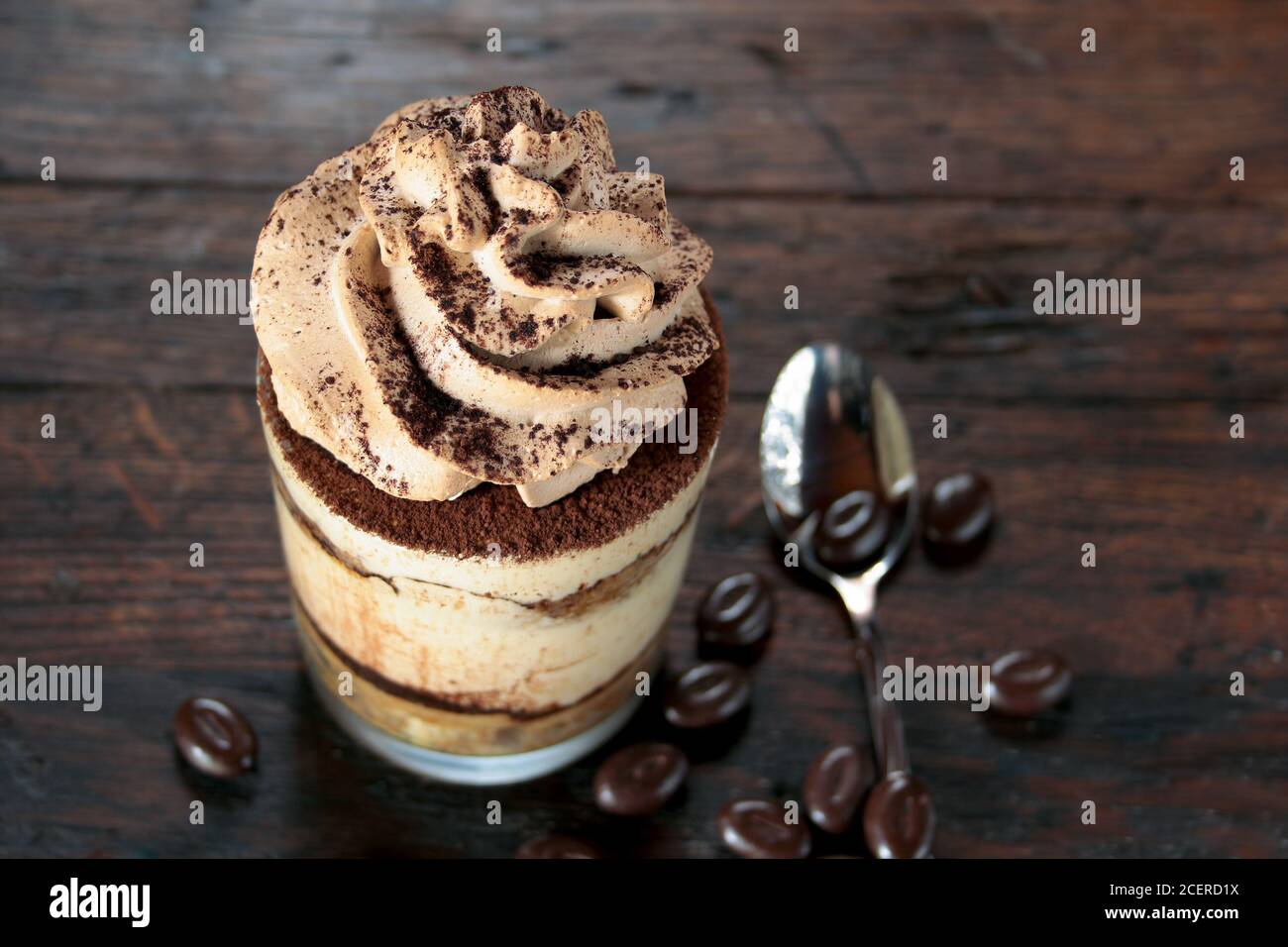 Dessert italiano tiramisù in un bicchiere su sfondo ligneo Foto Stock