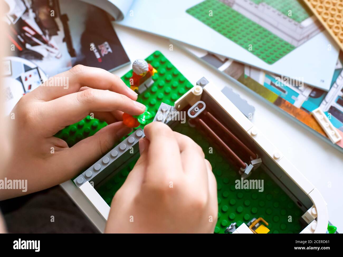 Tambov, Federazione Russa - 20 Giugno 2020 Bambino costruzione casa Lego sul tavolo con libri di istruzioni. Profondità di campo poco profonda Foto Stock