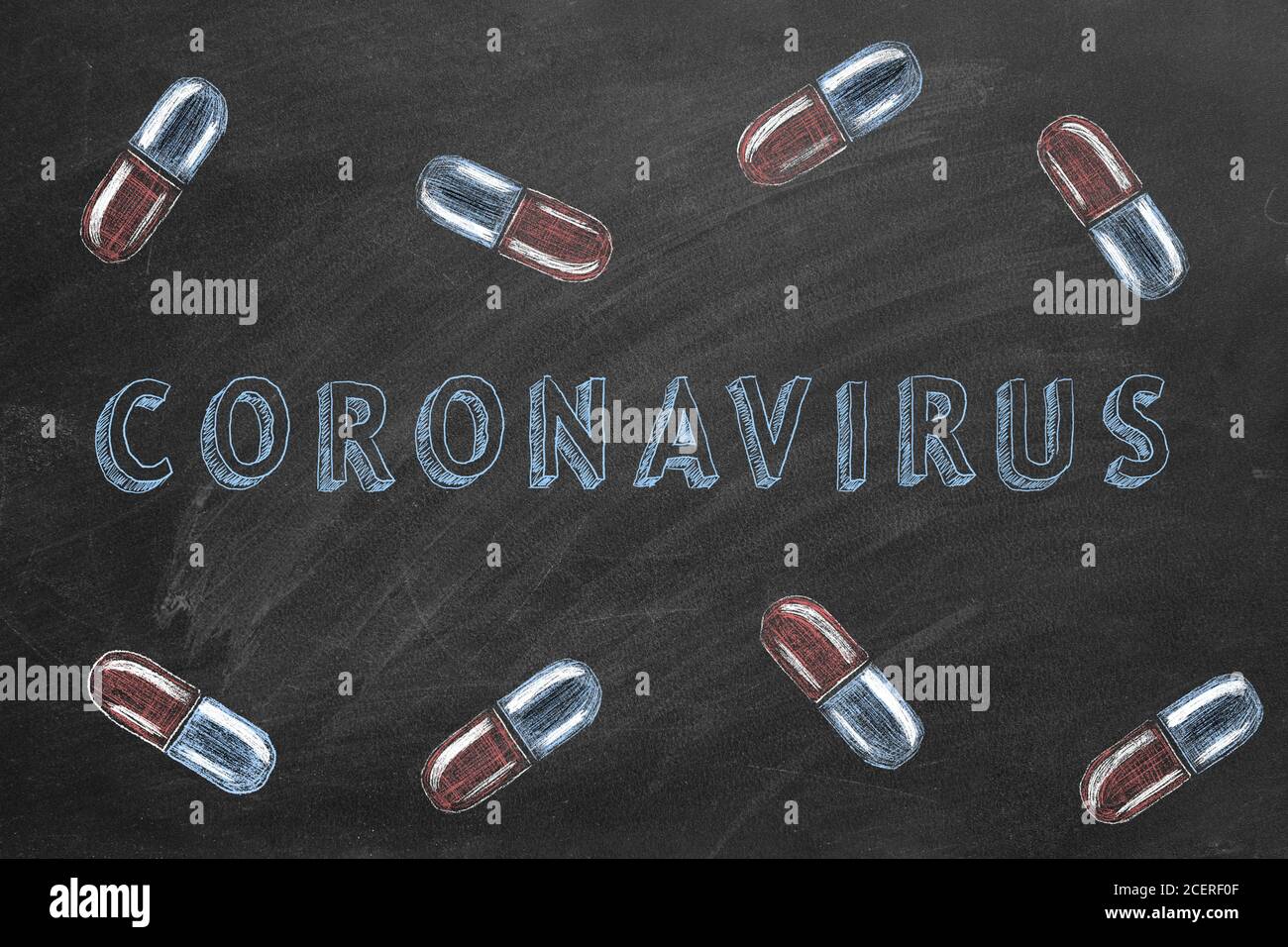 Mano che disegna il testo 'CORONAVIRUS' e cadere giù le pillole sulla lavagna. Foto Stock