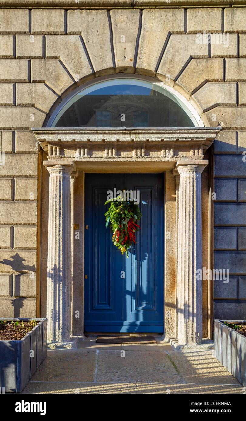 Porta blu georgiana con corona verde natalizia e bacche rosse. Ingresso con colonne in pietra e fanale con finestra ad arco. Dublino, Irlanda Foto Stock
