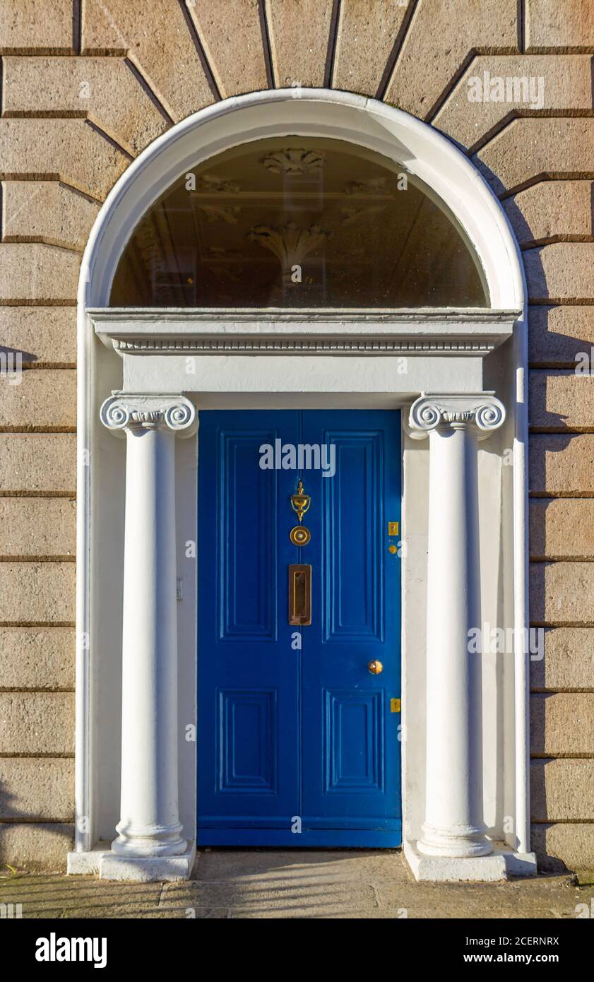 Porta blu georgiana, entrata frontale esterna, con fanale ad arco a finestra, colonne e classico pomolo in ottone, batticalcagno e scatola di lettere. Dublino, Irlanda Foto Stock