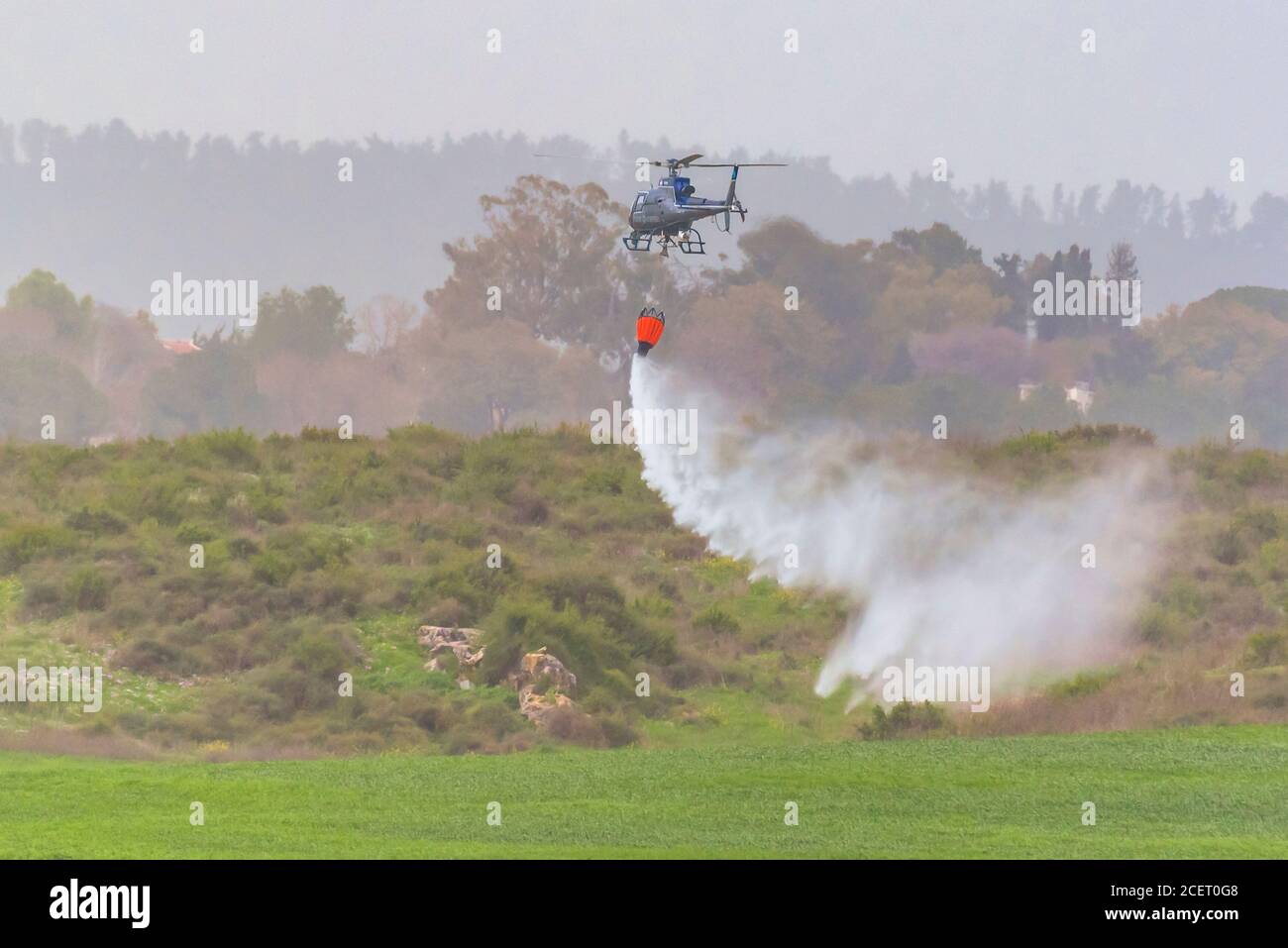 Un elicottero di polizia è utilizzato durante un incendio trapano a. Acqua dell'ascensore alla zona di fuoco l'acqua viene fatta cadere nell'area richiesta Foto Stock