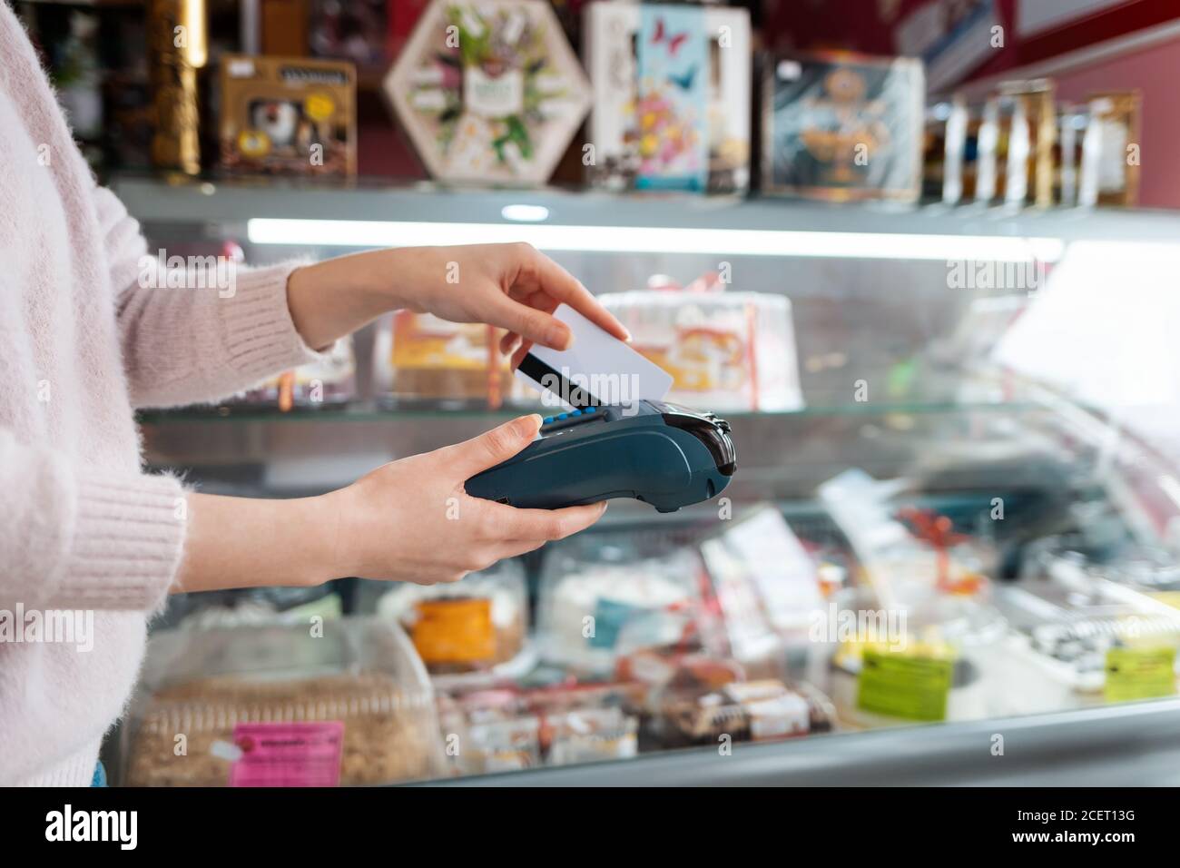 La donna passa una carta bancaria attraverso la macchina di pagamento per completare il pagamento dell'acquisto. Primo piano delle mani. Concetto NFC, attività commerciali e operazioni bancarie Foto Stock