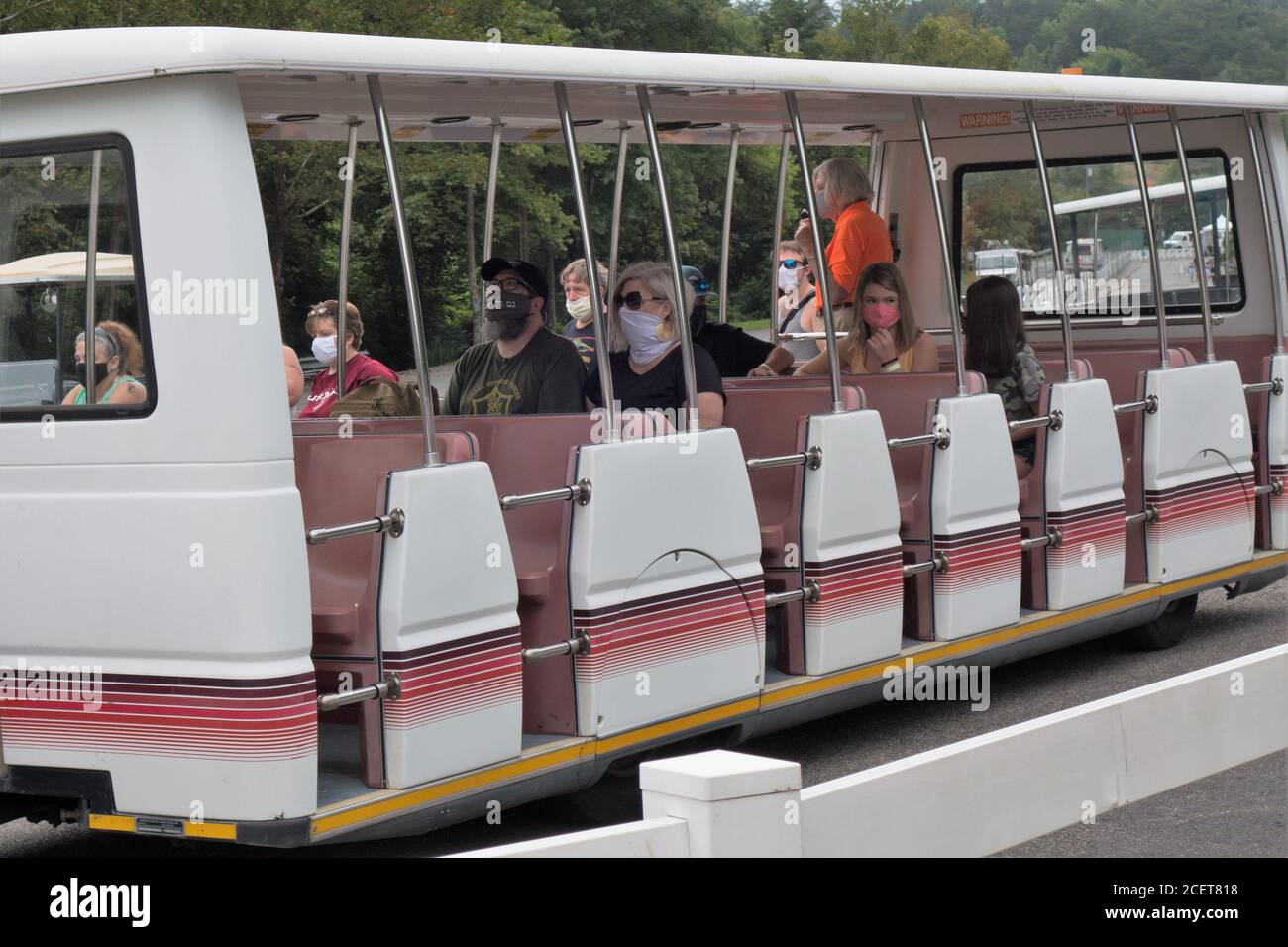 Le persone che indossano maschere facciali e socialmente distanziate cavalcano un tram per Dollywood a Pigeon Forge, TN, USA. Foto Stock