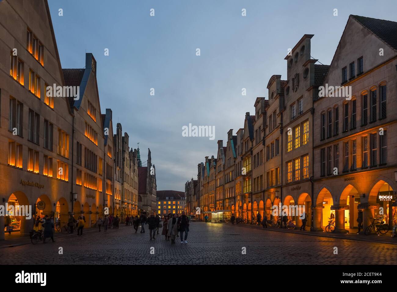 Muenster, Prinzipalmarkt con le sue vecchie case a timpano al tramonto, ora blu, le persone passeggiando per la famosa strada dello shopping, antica strada acciottolata, Foto Stock