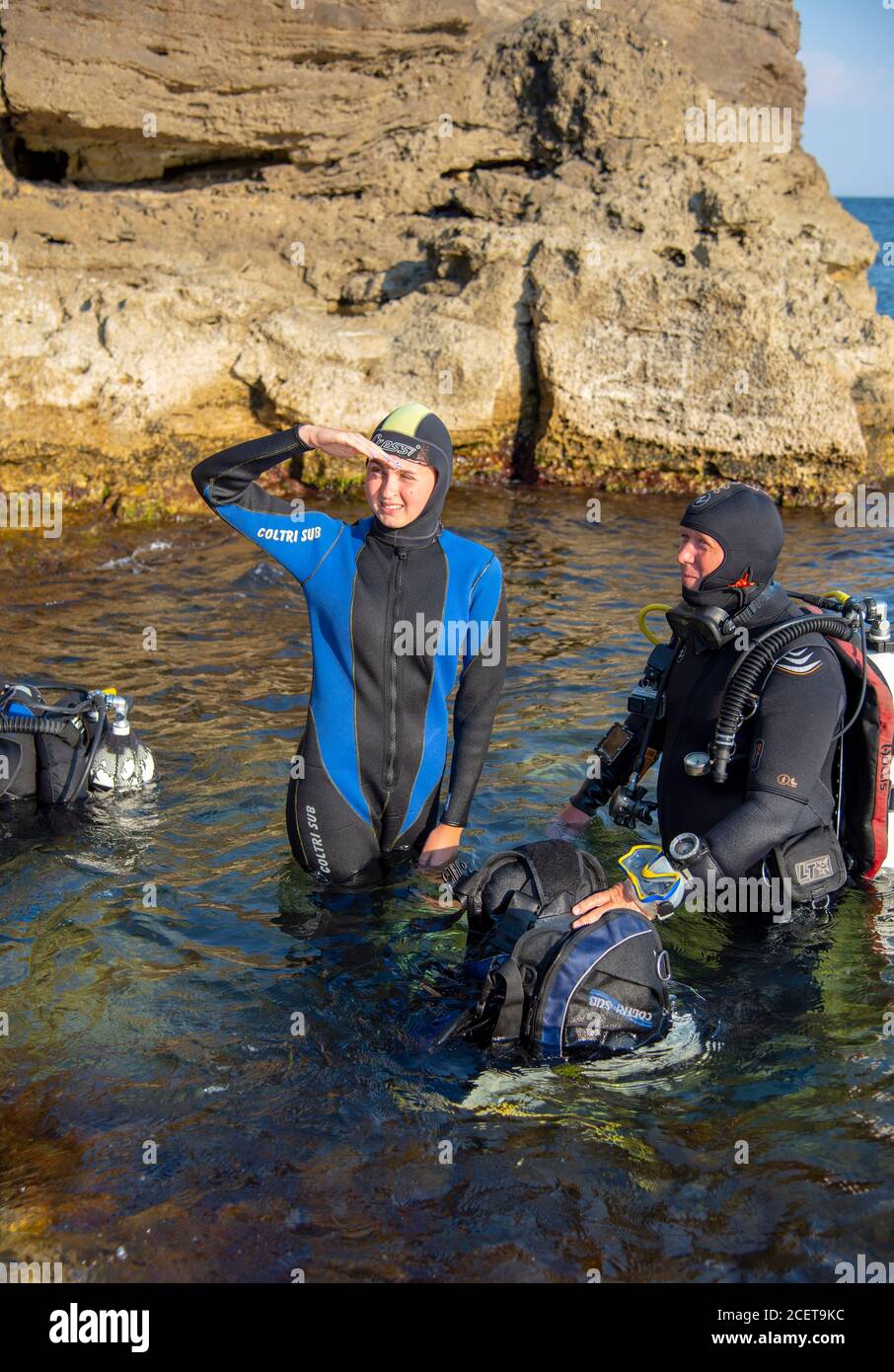 Le persone in mute e attrezzatura subacquea si preparano a tuffarsi in acqua. Foto Stock