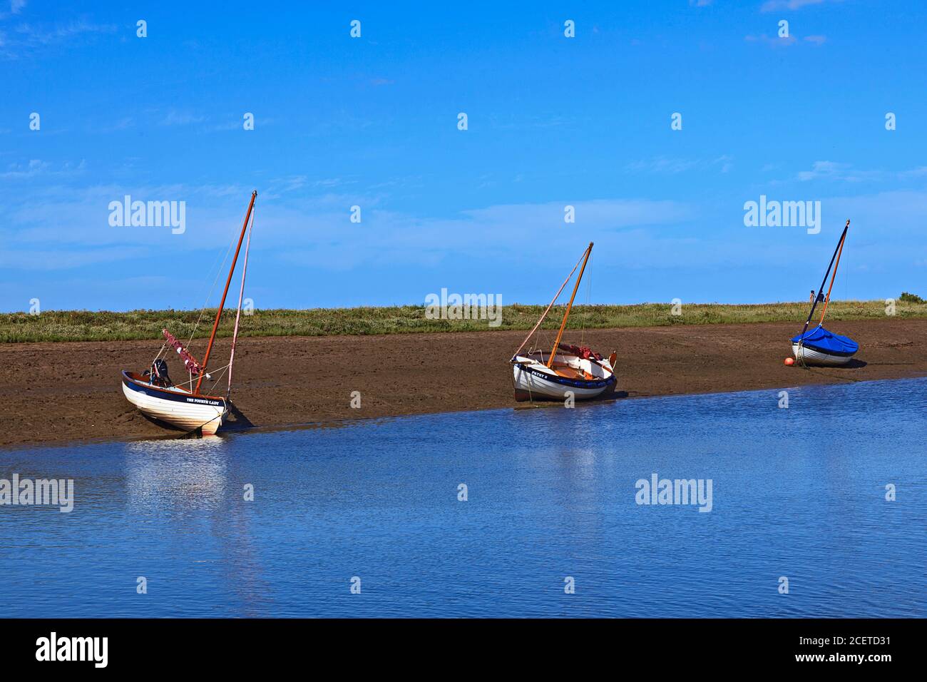 Barche a bassa marea a Burnham-Overy-Staithe sulla costa di Norfolk, Regno Unito Foto Stock