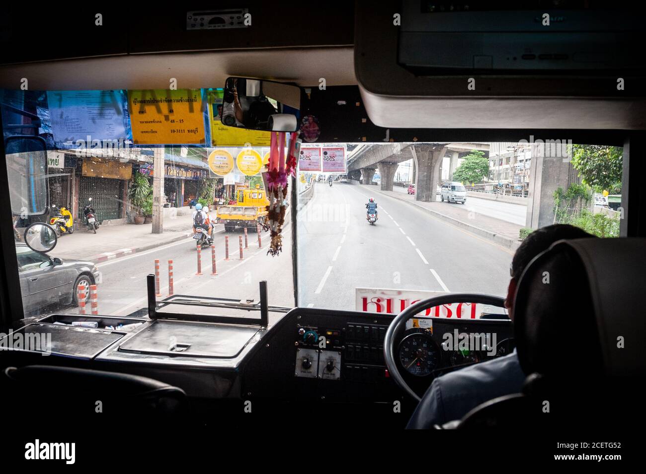Una foto che guarda attraverso la finestra frontale di un tipico autobus pubblico thailandese che guida lungo Sukhumvit Rd. Bangkok, Thailandia. Foto Stock