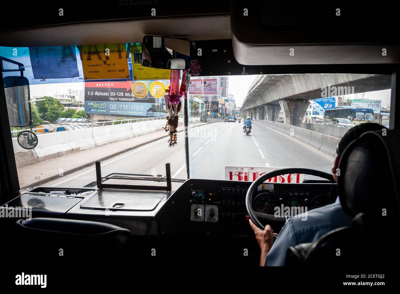 Una foto che guarda attraverso la finestra frontale di un tipico autobus pubblico thailandese che guida lungo Sukhumvit Rd. Bangkok, Thailandia. Foto Stock